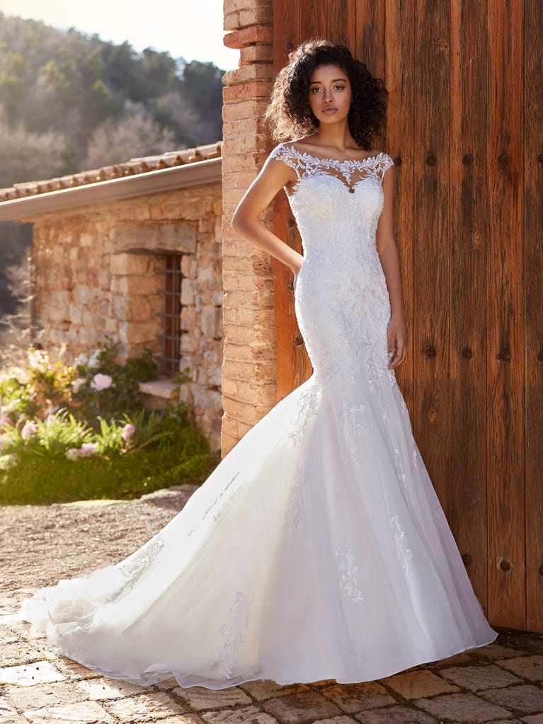 Ein Traum aus Spitze ist dieses umwerfende Kleid im Meerjungfrau-Stil mit zwei Lagen: Spitze über einem Unterkleid mit herzförmigem Dekolleté. Die zarten Flügelärmel bilden einen hübschen Kontrast zum sexy Keyhole-Rücken.