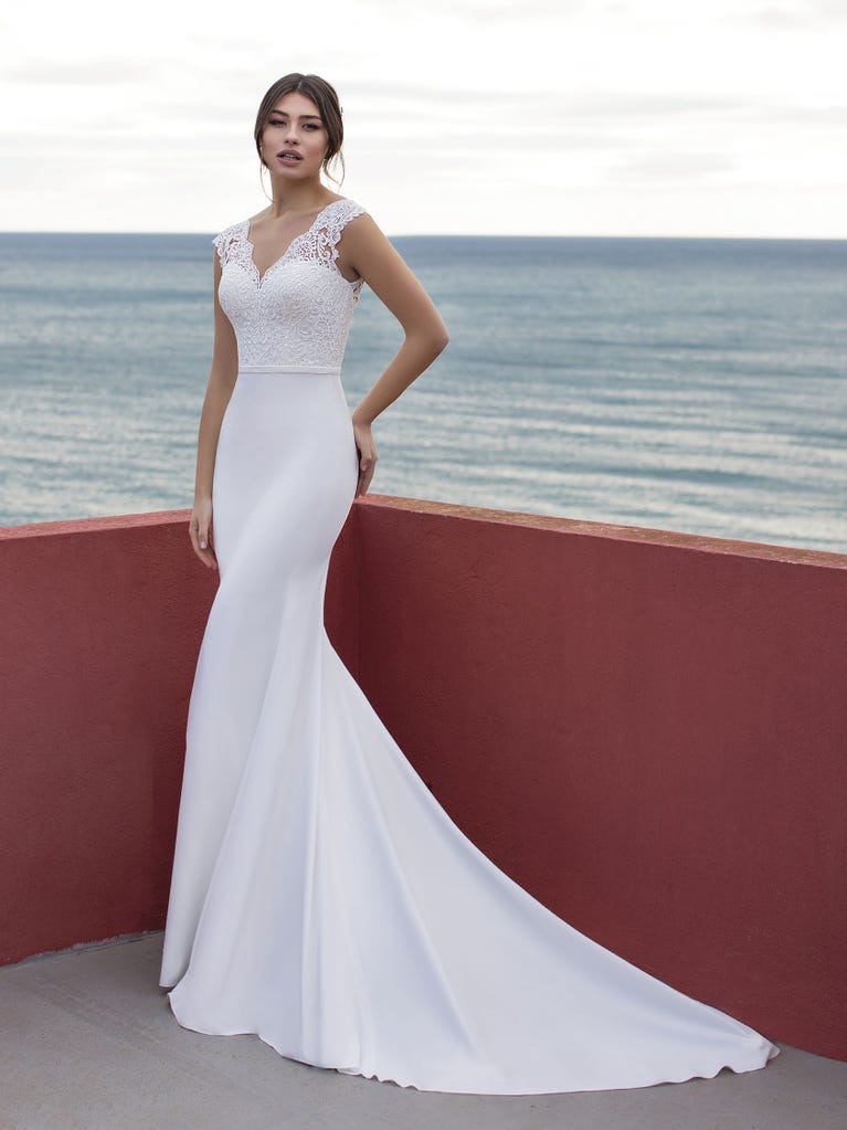 Ein Traum aus Spitze ist dieses umwerfende Kleid im Meerjungfrau-Stil mit zwei Lagen: Spitze über einem Unterkleid mit herzförmigem Dekolleté. Die zarten Flügelärmel bilden einen hübschen Kontrast zum sexy Keyhole-Rücken.
